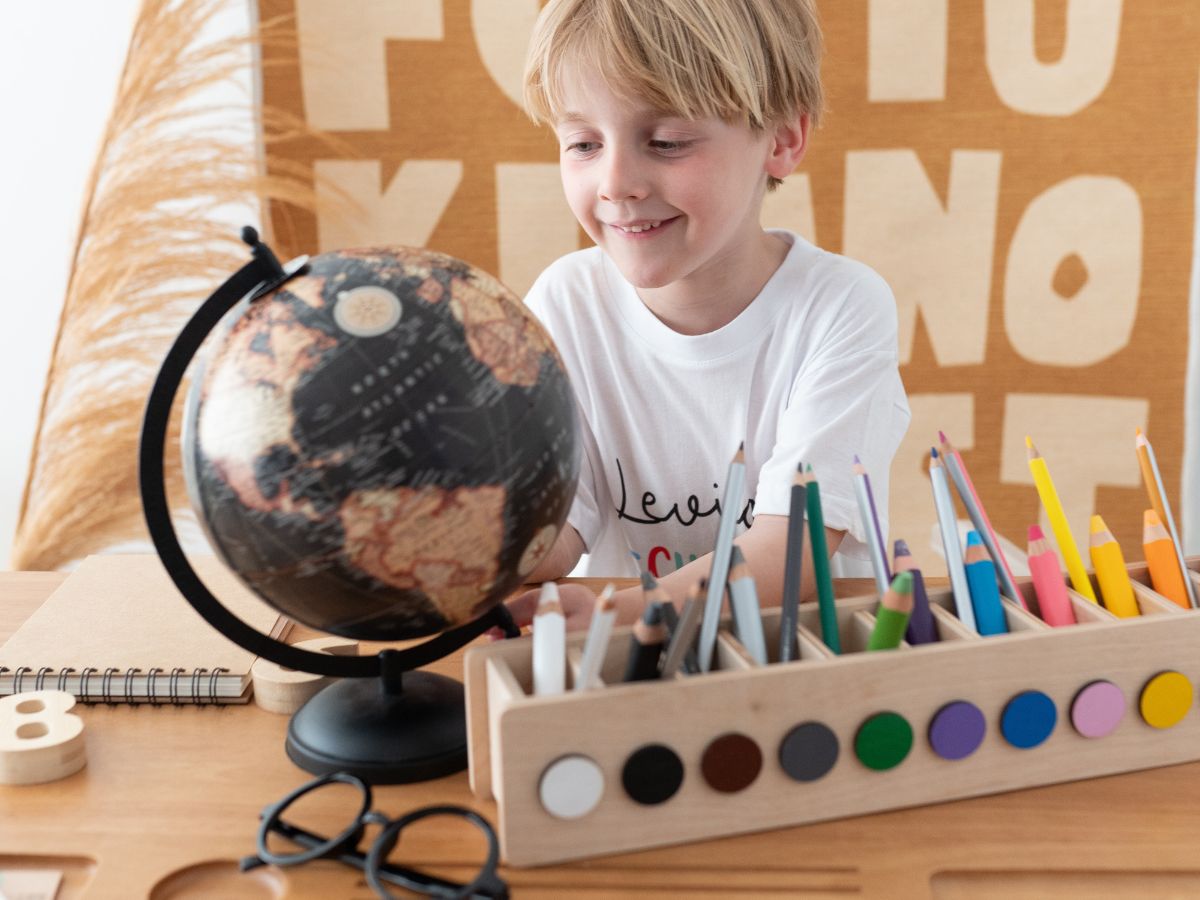 Schulkind mit Globus und Stiftebox