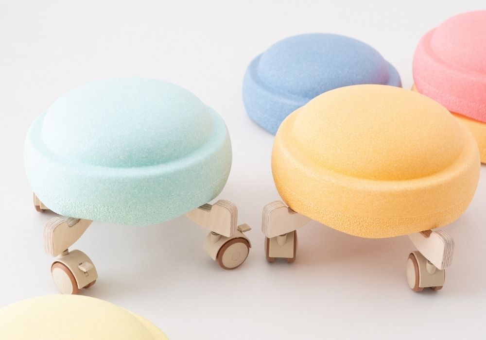 Pastellfarbene Stapelsteine auf Holz Rollern als Zubehör für Bewegungsparcours im Kinderzimmer